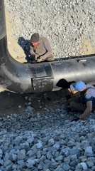 Two workers inspect large pipe in Leninsk, Russia