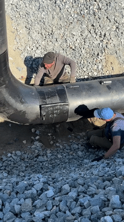 Two workers inspect large pipe in Leninsk, Russia
