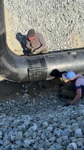 Two workers inspect large pipe in Leninsk, Russia