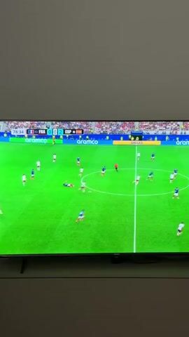 The video shows a television screen displaying a soccer match. The score is France 0, Spain 2. The clock shows 78:36. In the foreground, a soccer player in a blue jersey with the number 5 on it is looking to his right. In the background, the soccer field is visible, with players in white and blue jerseys. A referee in a red shirt is shown pointing to his right, and then a player in a white jersey is seen. The scene is well-lit, and the image quality is clear.