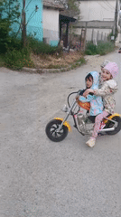 Children ride toy motorcycles on Bulgarian village street