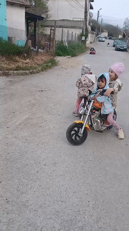 Children ride toy motorcycles on Bulgarian village street