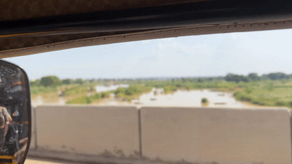 Driver records bridge view of brown river with vegetation islands