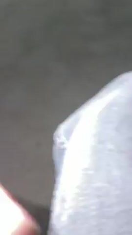 A man, presumably named Hassan, is speaking into a camera. He is wearing a gray puffy jacket. Behind him is a metal fence. The video is taken at night.
