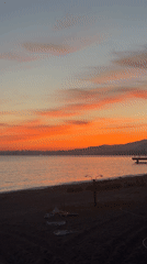 Woman documents sunset moment in bathrobe at Abkhazia coast