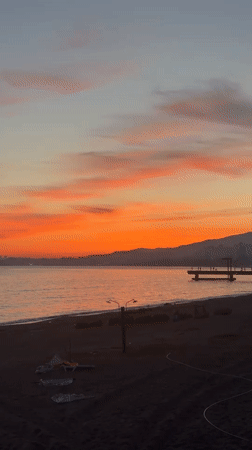 Woman documents sunset moment in bathrobe at Abkhazia coast