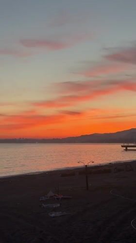 Woman documents sunset moment in bathrobe at Abkhazia coast