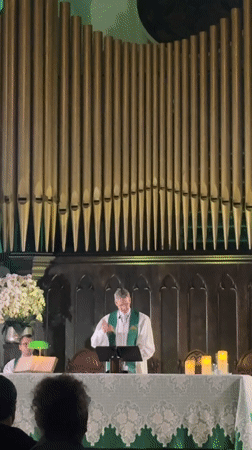 Church service underway in São Paulo, pipe organ glowing behind the lectern