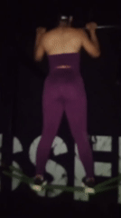 Person performs assisted pull-ups in purple athletic wear
