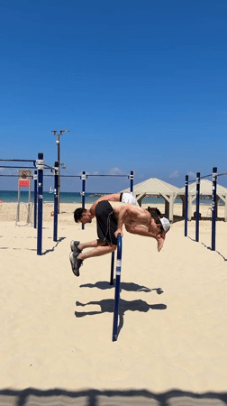 Two men perform morning calisthenics workout on Tel Aviv beach