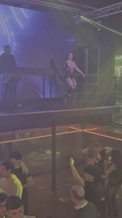 Dance performer entertains nightclub crowd from elevated platform in Prague