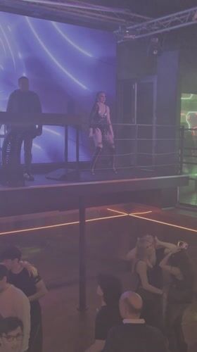 Dance performer entertains nightclub crowd from elevated platform in Prague