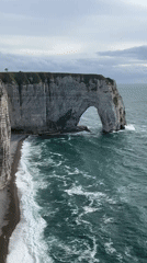 Tourists explore Étretat's famous chalk cliffs by land and sea