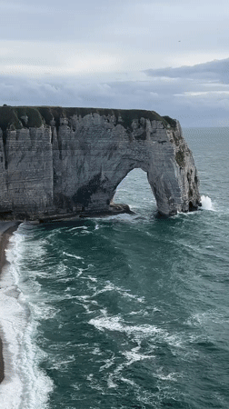 Tourists explore Étretat's famous chalk cliffs by land and sea