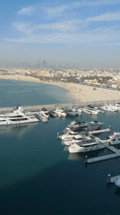 Dubai waterfront scene shows boats, beach activity from above