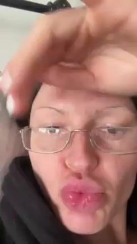 A person wearing glasses and a black hoodie lies in bed and waves their hand at the camera. The bed has a metal headboard. The person says, "It's your bestie Ms. Ms. Westie." The video is shot from a close-up, eye-level perspective.