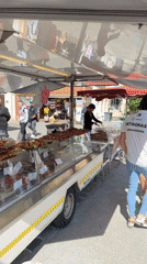Food vendor serves customers at outdoor market in Grimaud