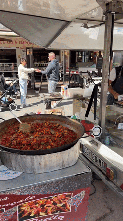 Food vendor serves customers at outdoor market in Grimaud