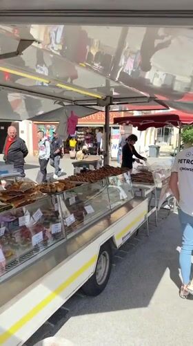Food vendor serves customers at outdoor market in Grimaud
