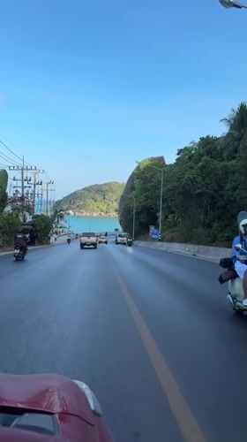 Traffic flows on wet coastal road in Thailand