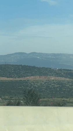 Car drives through hilly Israeli landscape near Galil Tachton