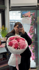 Woman takes selfie with pink flower bouquet in Liepāja shop