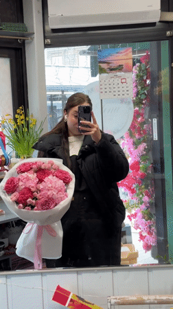 Woman takes selfie with pink flower bouquet in Liepāja shop