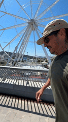 Tourist strolls Barcelona waterfront near Ferris wheel and W Hotel