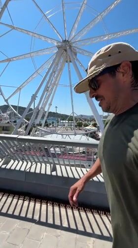 Tourist strolls Barcelona waterfront near Ferris wheel and W Hotel