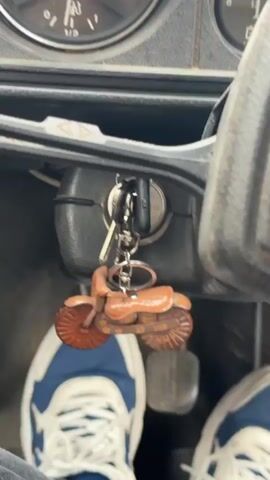 The video shows the interior of a car, focusing on the dashboard. A hand turns a knob on the dashboard, then the engine starts. An Angry Birds plush toy sits on the dashboard. The camera focuses on the interior, showing the steering wheel, the key in the ignition, and the pedals.