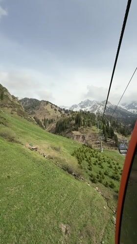 Spring cable car ride captures green slopes, snowy peaks near Almaty