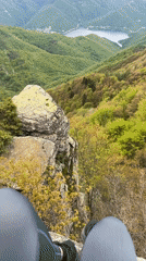 Person sits on rocky promontory overlooking Bulgarian mountain vista