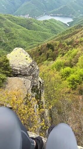 Person sits on rocky promontory overlooking Bulgarian mountain vista