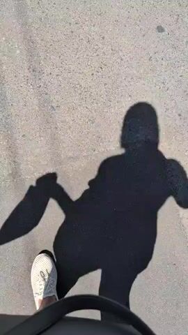 The video shows a shadow of a person walking on a paved surface, possibly a sidewalk or road. The shadow is cast by sunlight, indicating it is daytime. The person's shadow appears to be wearing athletic shoes and is in motion, with one leg extended forward. The overall scene is simple, focusing on the interplay of light and shadow. There is no visible text or identifying landmarks. The location is identified as Izmail, Ukraine, but this context is not visually apparent within the footage.