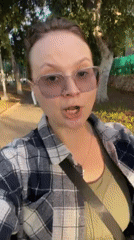 Woman in plaid shirt speaks to camera on Tel Aviv sidewalk