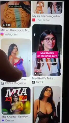 A finger on a person's hand scrolls down a Google search results page for Mia Khalifa. Several thumbnails appear, displaying various images and videos featuring the subject. The results include links to Instagram, PAPER Magazine, TikTok, Deezer, and Ubuy Palestine. Some images are sexually suggestive.