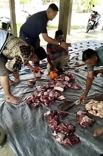 Men process meat outdoors in Meunasahalue, Indonesia