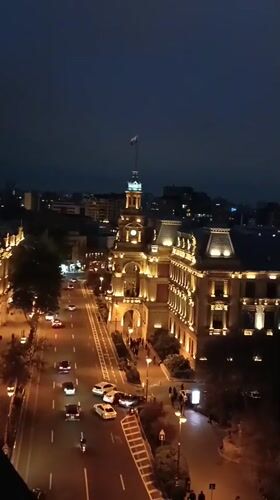Night scene captures busy Baku street, illuminated historic building