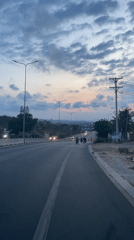 Routine traffic flows downhill on illuminated Vietnam street