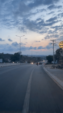 Routine traffic flows downhill on illuminated Vietnam street