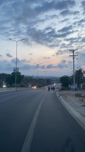 Routine traffic flows downhill on illuminated Vietnam street