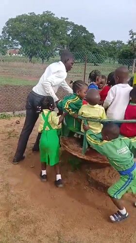 Children play on colorful playground equipment in Akwanga, Nigeria