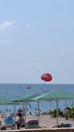 Red parasail over a packed Kemer beach on a summer morning
