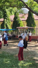 School children gather outdoors in bright sunlight in Lhokseumawe