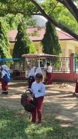School children gather outdoors in bright sunlight in Lhokseumawe