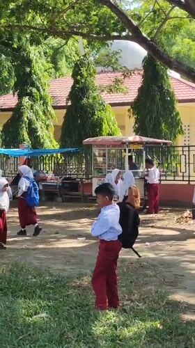 School children gather outdoors in bright sunlight in Lhokseumawe