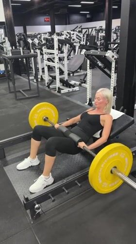 Woman performs barbell hip thrusts at Choeng Mon gym