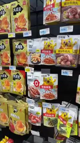 The video shows a shelf in a store. The shelf is stocked with various packages of preserved food items, possibly snacks or appetizers. Many of the packages feature images of meat products. Price tags are visible on each item. The video slowly pans across the shelf, displaying the range of products available.