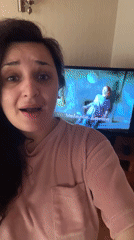 Woman films herself with TV showing video content behind