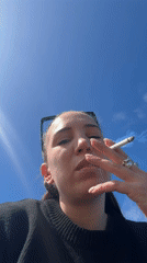 Woman smoking cigarette observed in Étretat, France